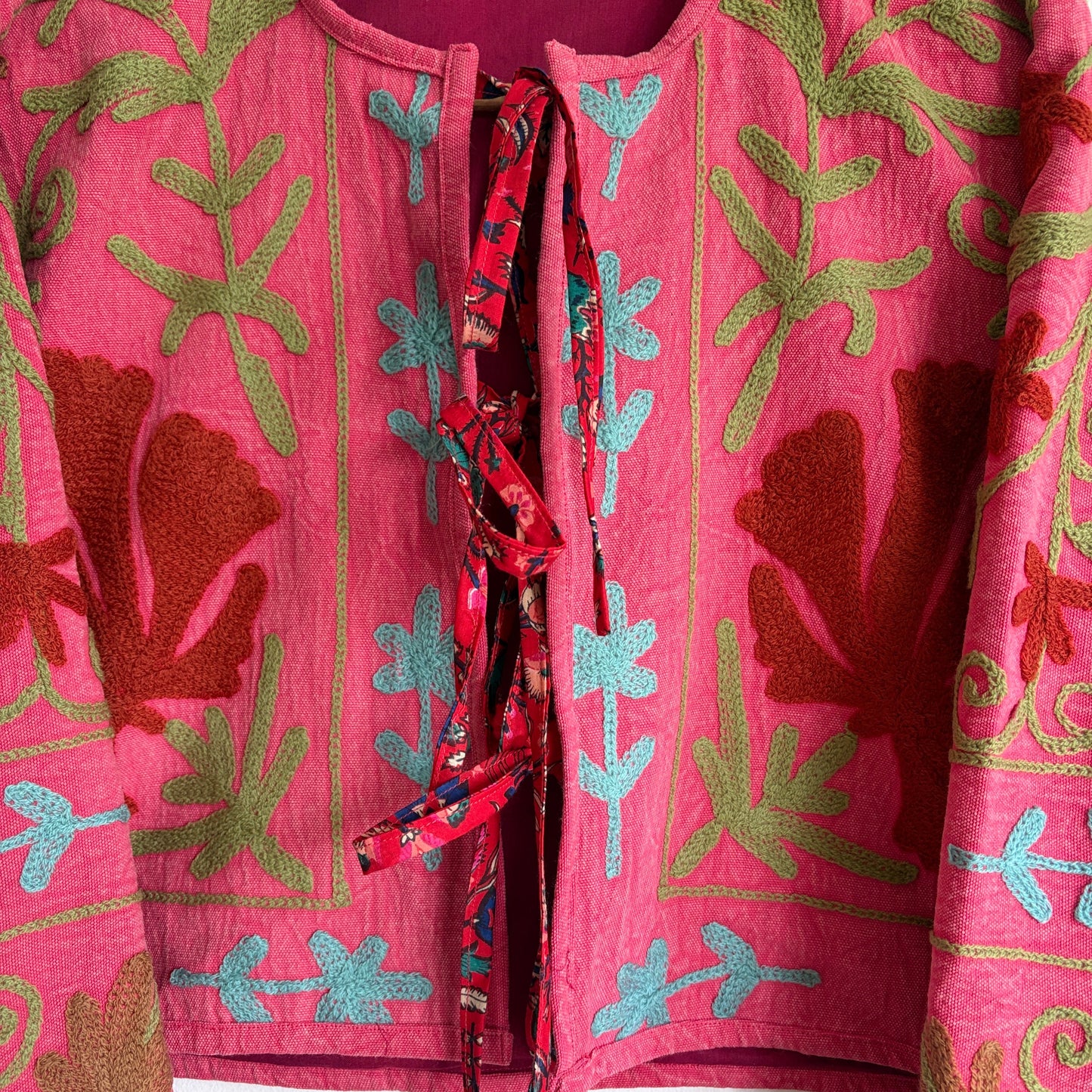 A cropped long-sleeve jacket with a vibrant pink and red floral pattern. 