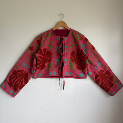 A cropped long-sleeve jacket with a vibrant pink and red floral pattern. 