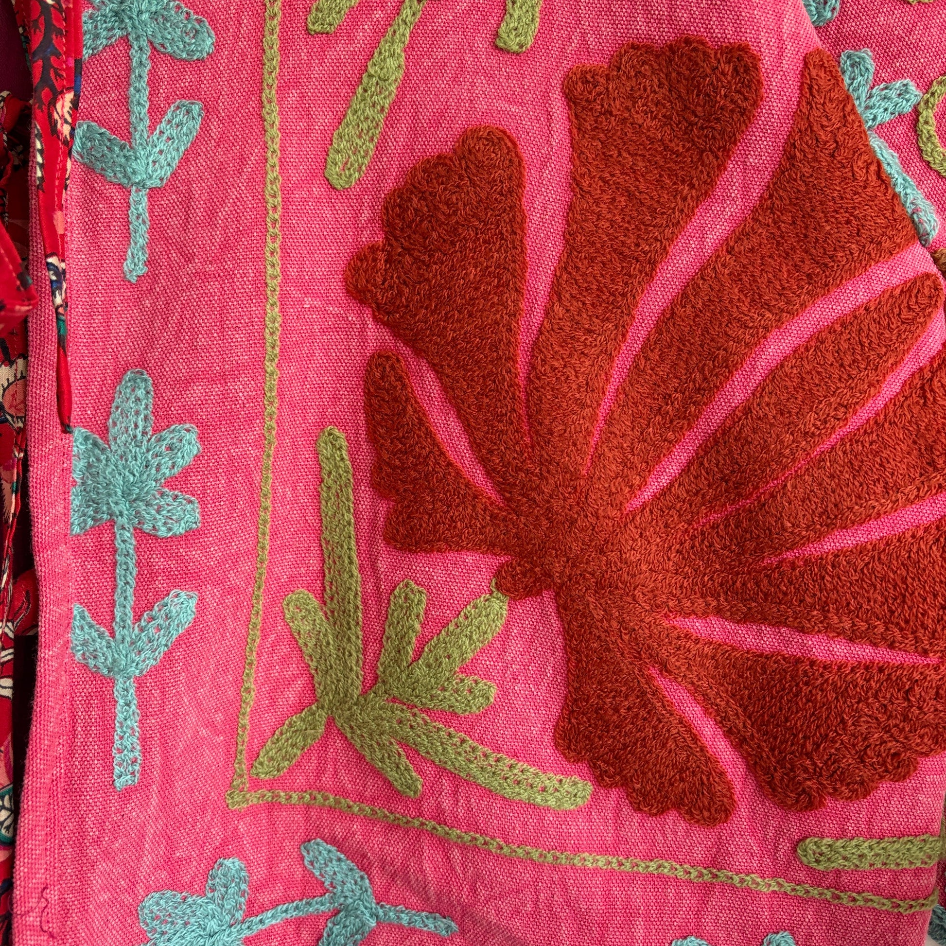 A cropped long-sleeve jacket with a vibrant pink and red floral pattern. 