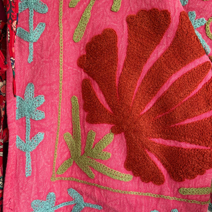 A cropped long-sleeve jacket with a vibrant pink and red floral pattern. 