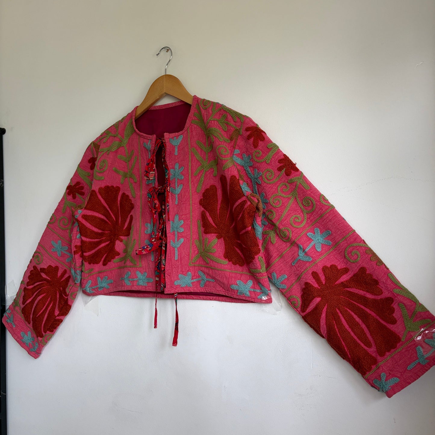 A cropped long-sleeve jacket with a vibrant pink and red floral pattern. 