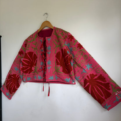 A cropped long-sleeve jacket with a vibrant pink and red floral pattern. 