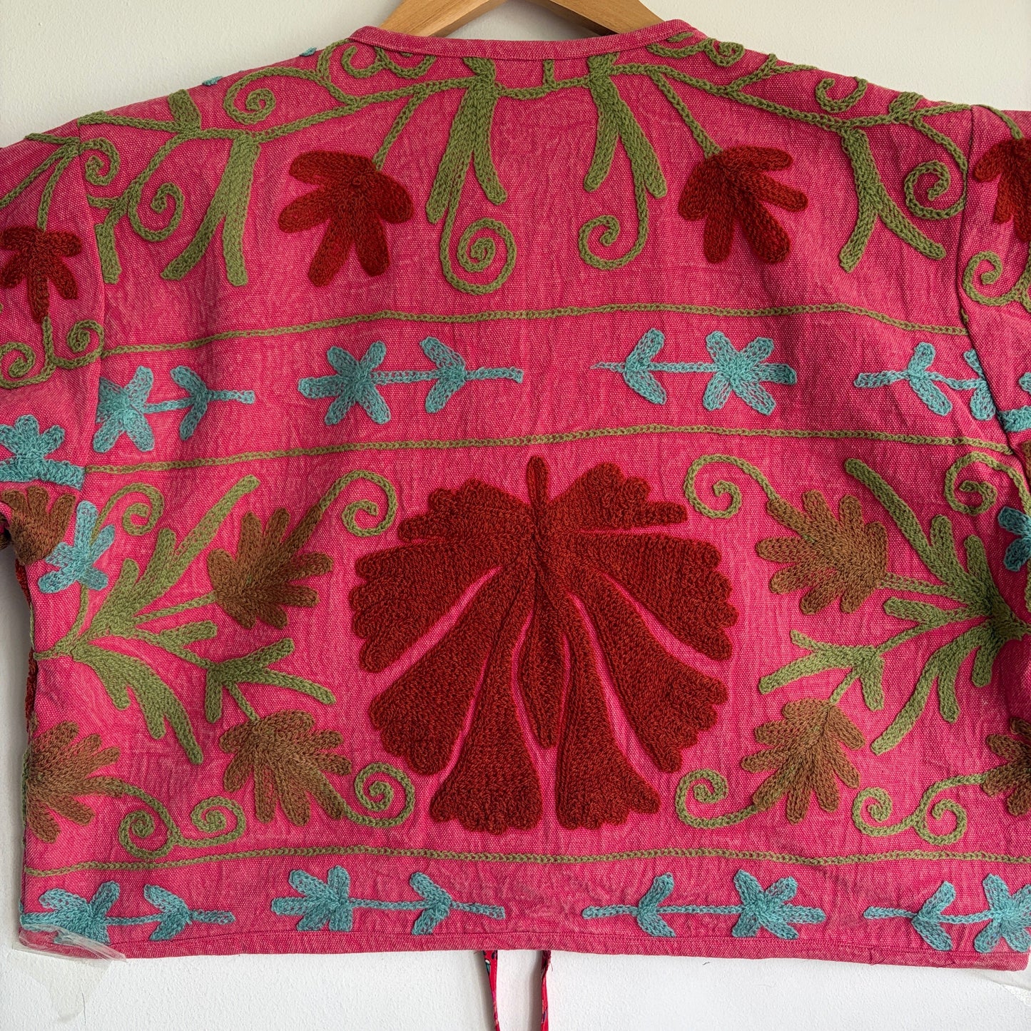 A cropped long-sleeve jacket with a vibrant pink and red floral pattern. 
