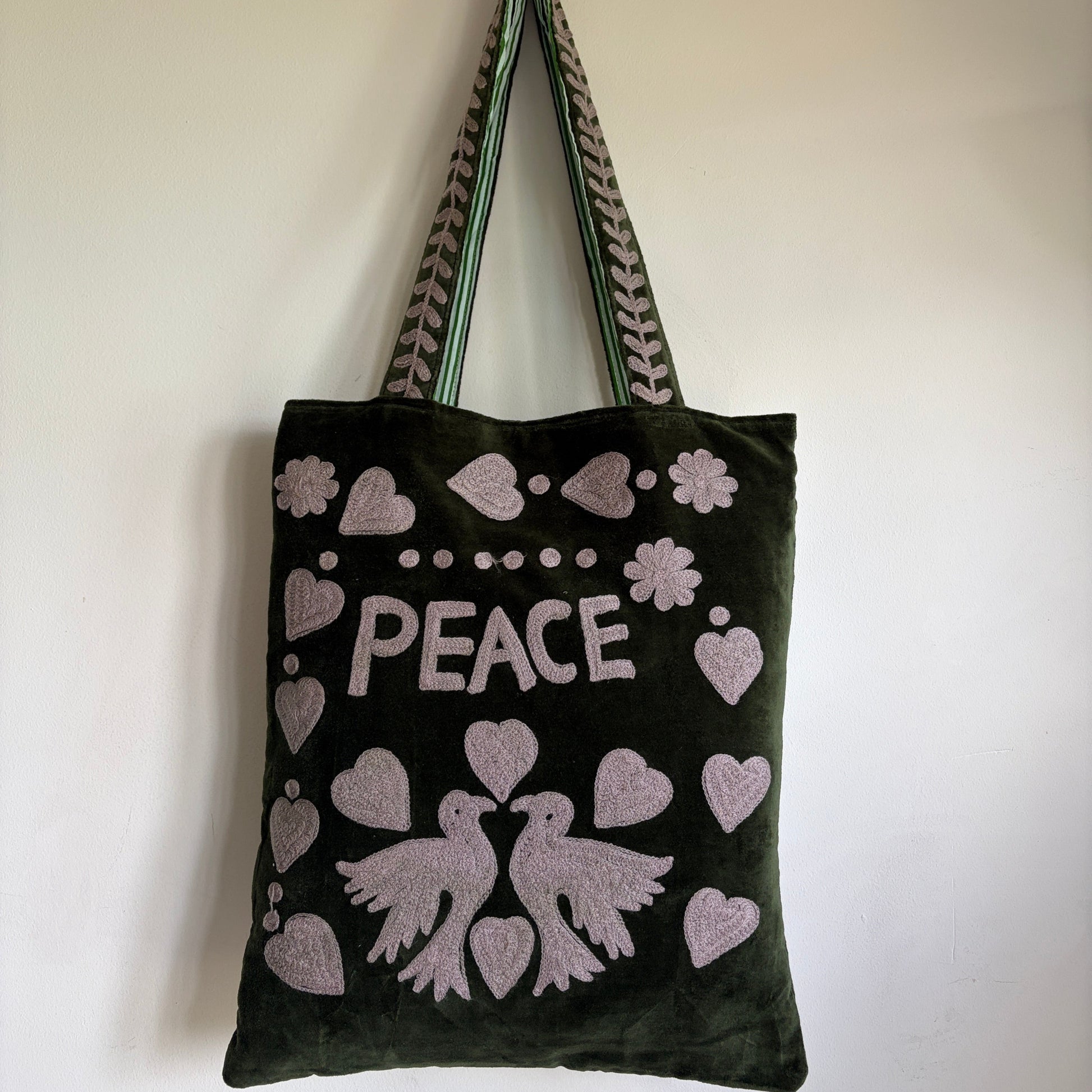 A dark green velvet tote bag featuring a 'PEACE' design with hearts, doves, and flowers in light pink.