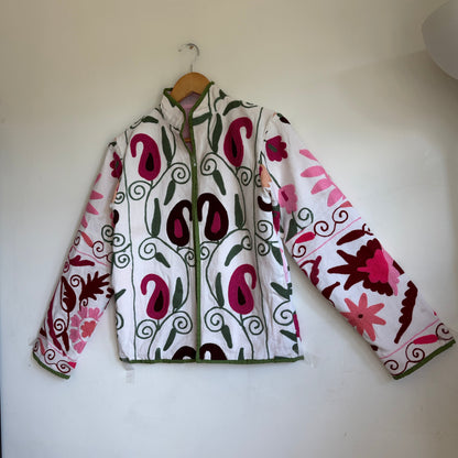 White quilted jacket with pink, green, and black embroidered paisley and floral patterns. 