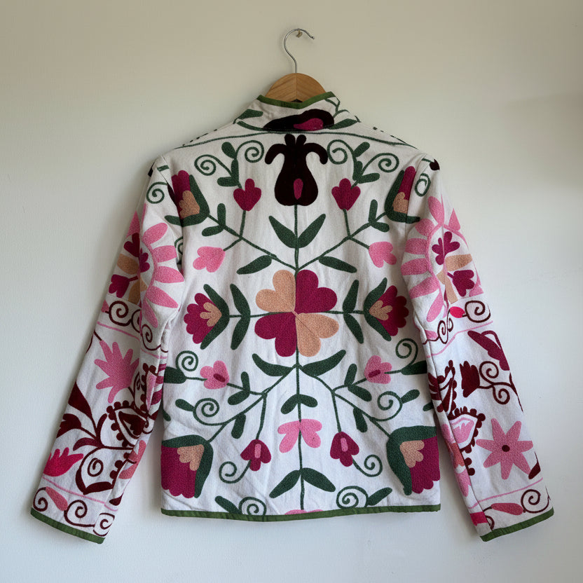 White quilted jacket with pink, green, and black embroidered paisley and floral patterns. 