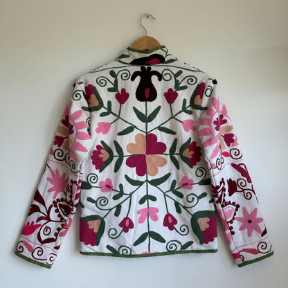 White quilted jacket with pink, green, and black embroidered paisley and floral patterns. 