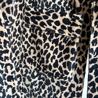 A leopard print robe hanging on a hanger against a plain white wall. 