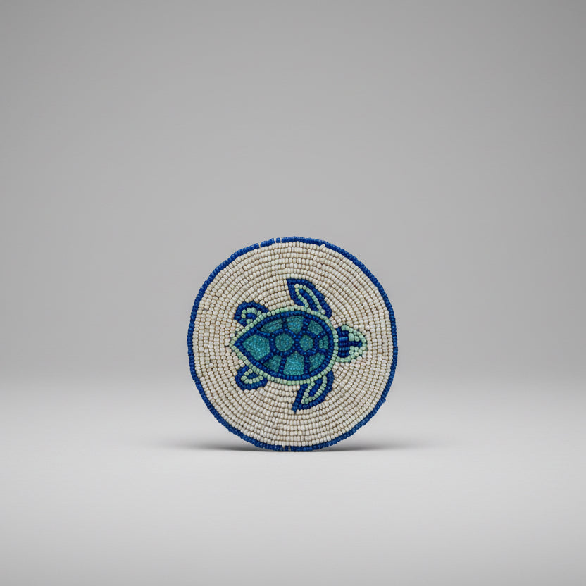 A round beaded coaster featuring a sea turtle design. 
