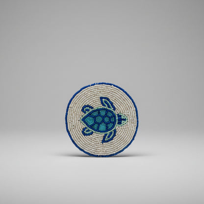 A round beaded coaster featuring a sea turtle design. 