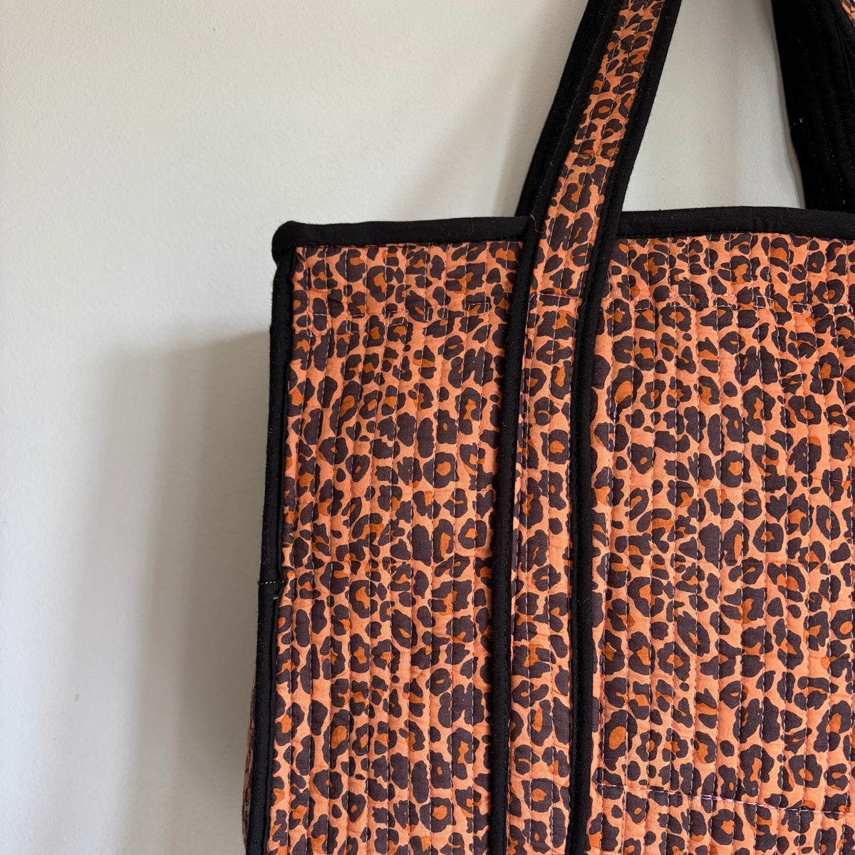 Leopard print tote bag with black trim and handles. 