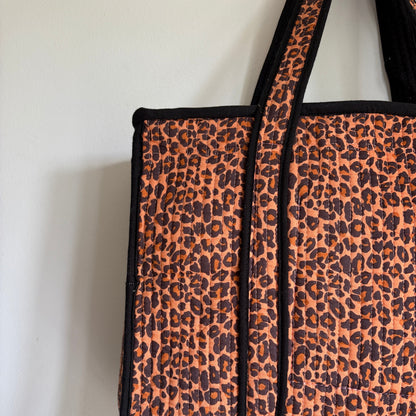 Leopard print tote bag with black trim and handles. 