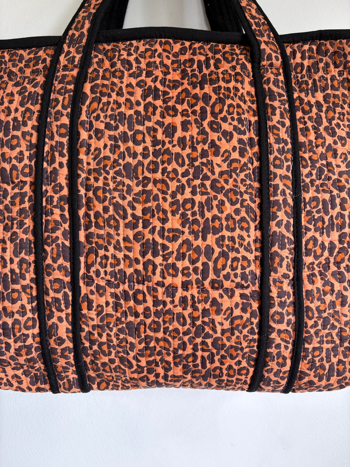Leopard print tote bag with black trim and handles. 