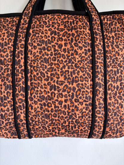 Leopard print tote bag with black trim and handles. 