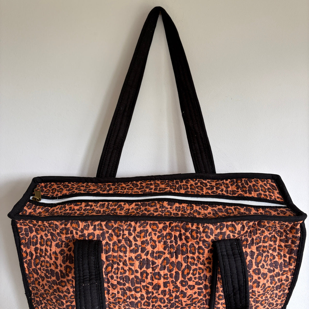 Leopard print tote bag with black trim and handles. 