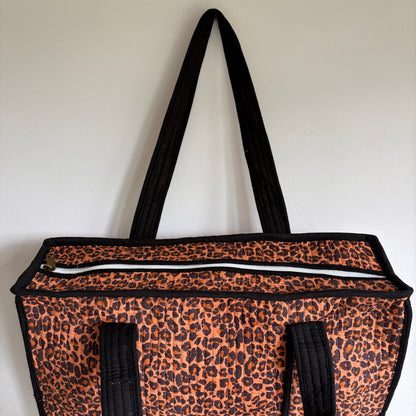 Leopard print tote bag with black trim and handles. 