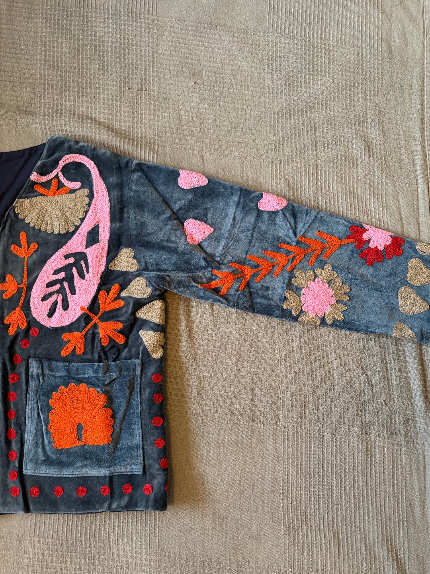 Embroidered denim fabric with floral and abstract designs on a textured surface