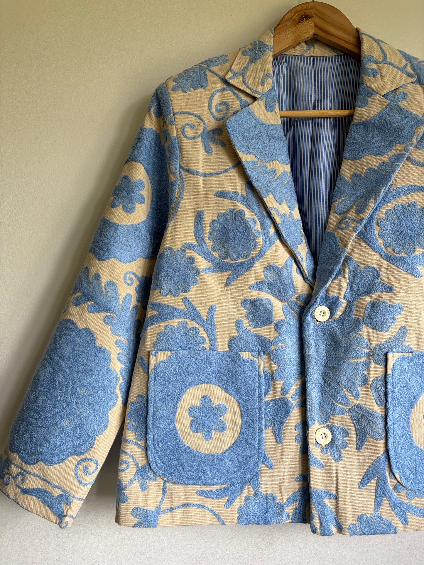 Floral patterned jacket on a hanger against a plain background
