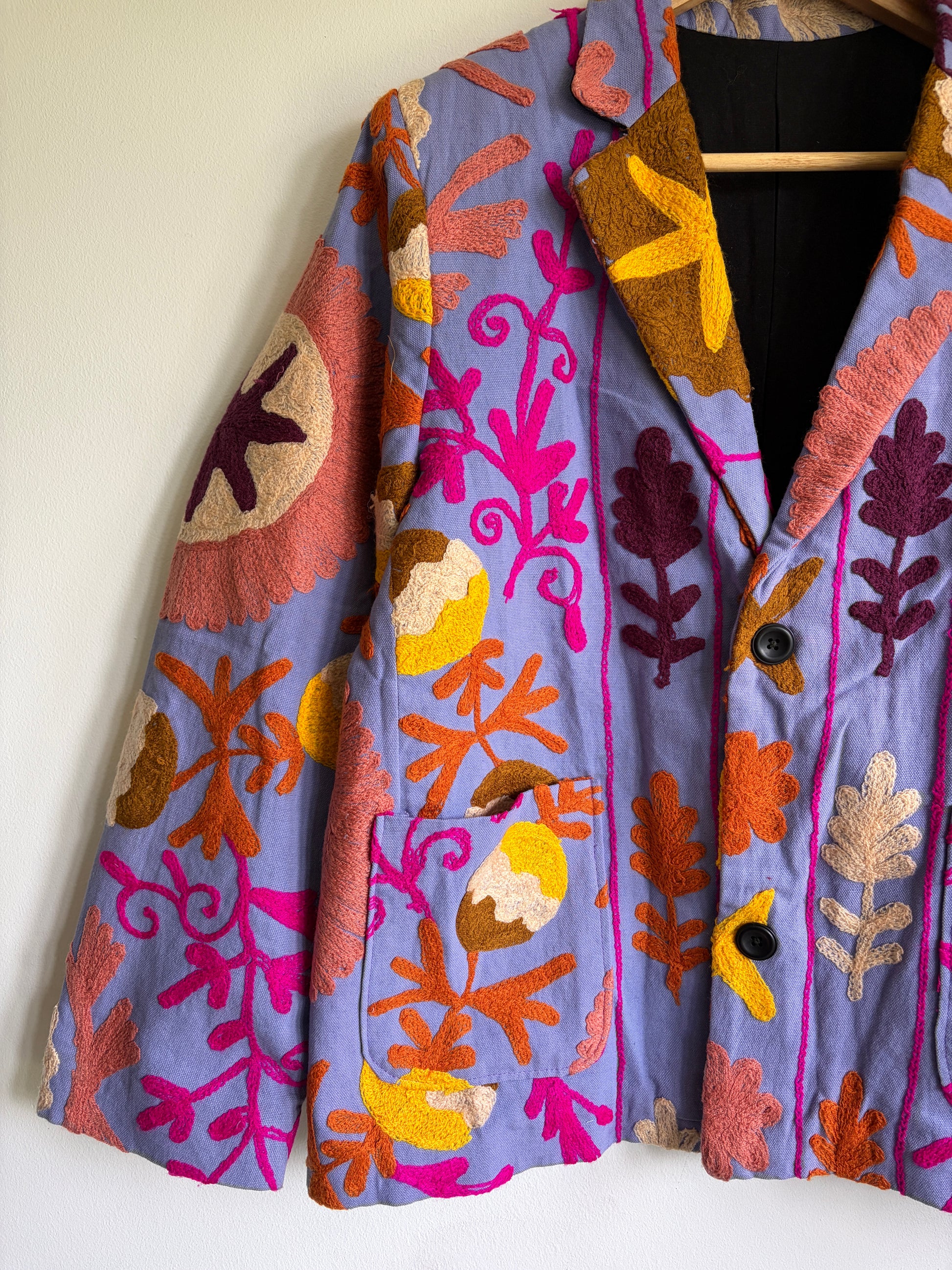 Colorful patterned coat with floral designs on a white background