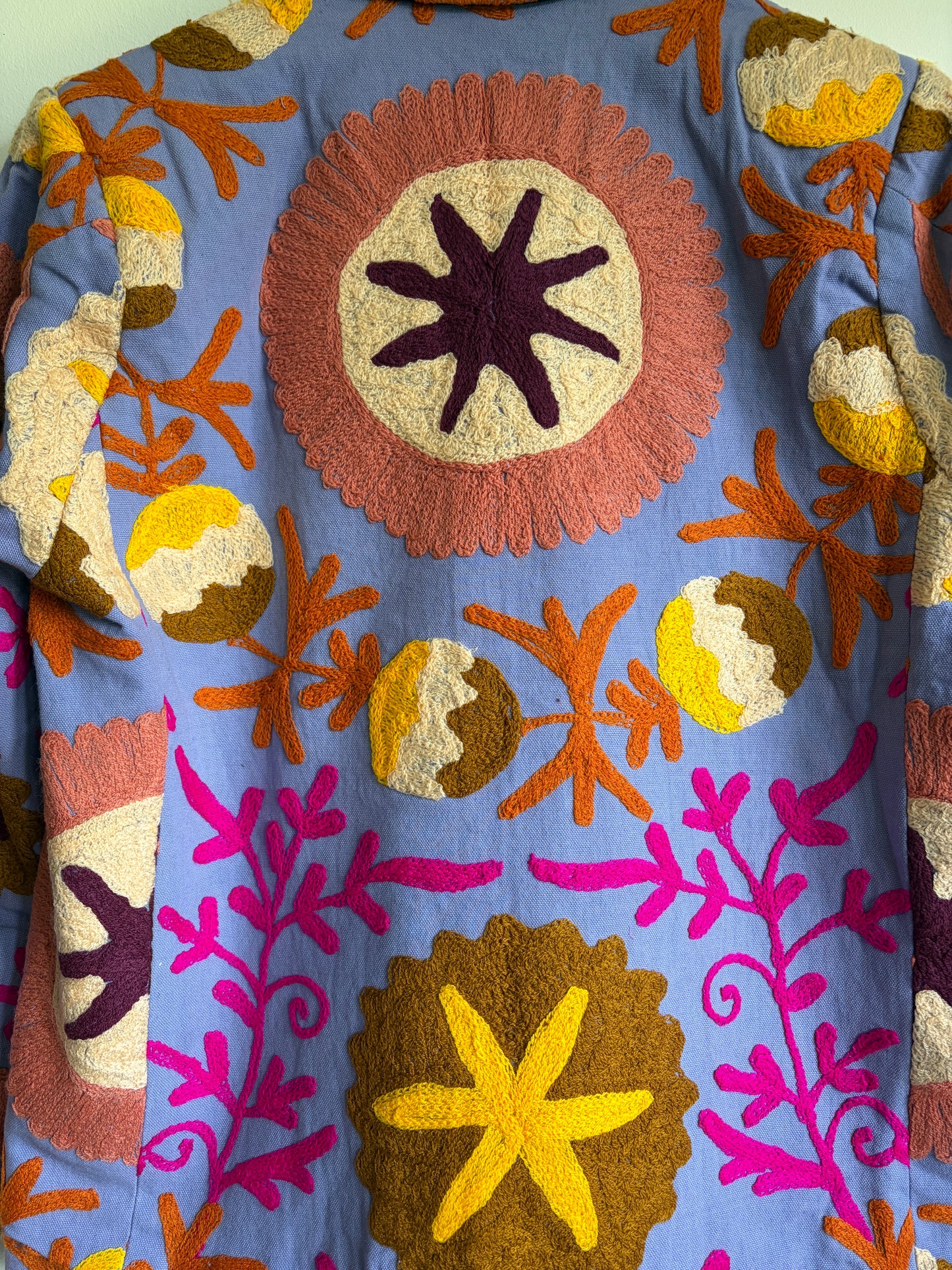 Colorful embroidered blazer with floral patterns on a blue background