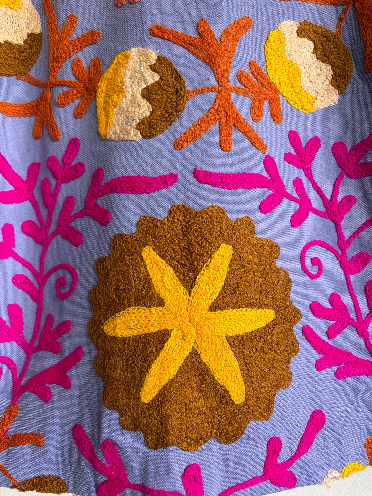 Colorful embroidered fabric with starfish and floral patterns on a blue background