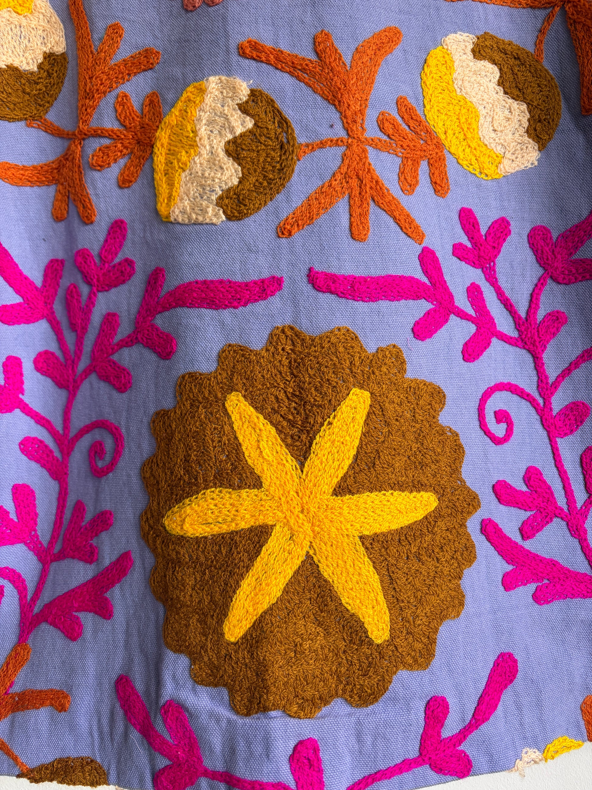 Colorful embroidered fabric with starfish and floral patterns on a blue background