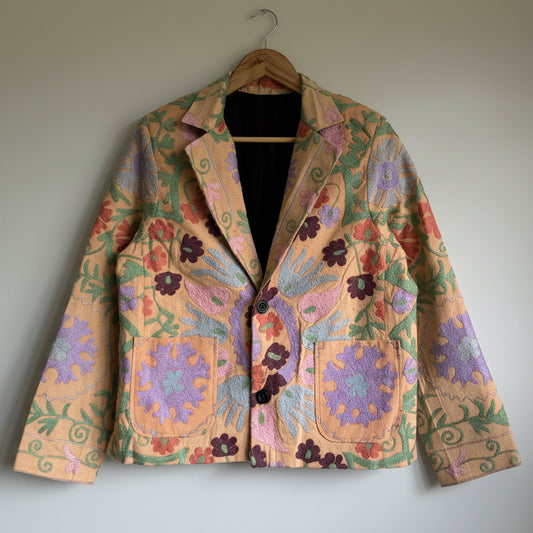 Colorful floral-patterned jacket on a hanger against a plain background