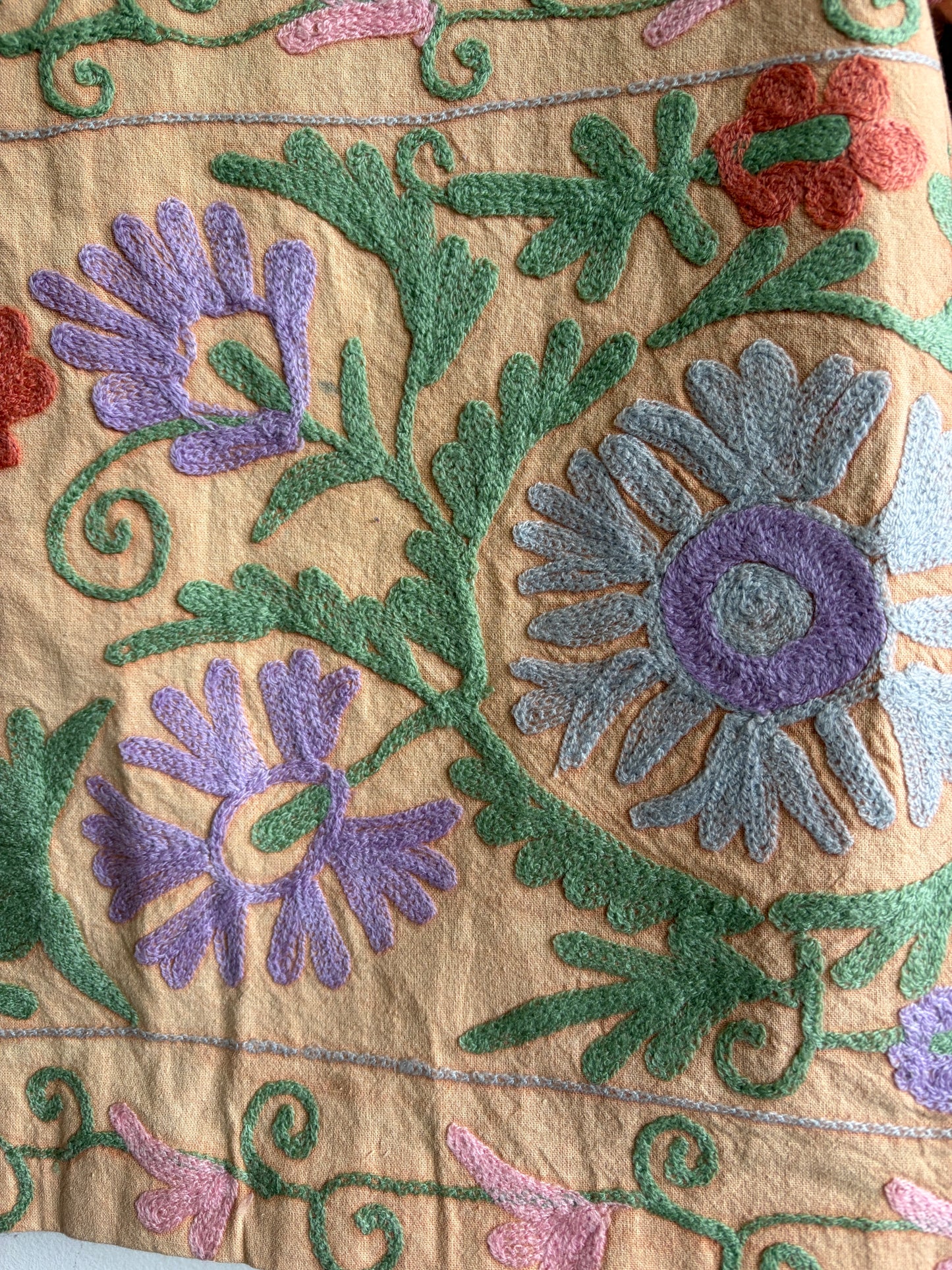 Suzani Floral Blazer with floral patterns in purple, green, and red on a beige background.