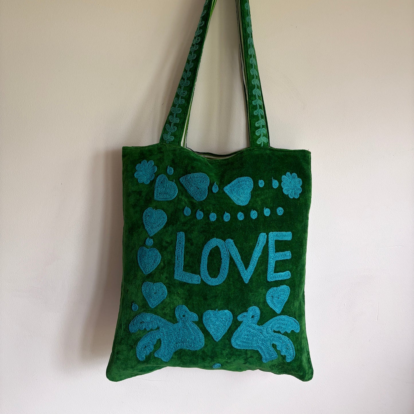 Green Suzani Velvet bag with blue hearts and 'LOVE' on a beige background