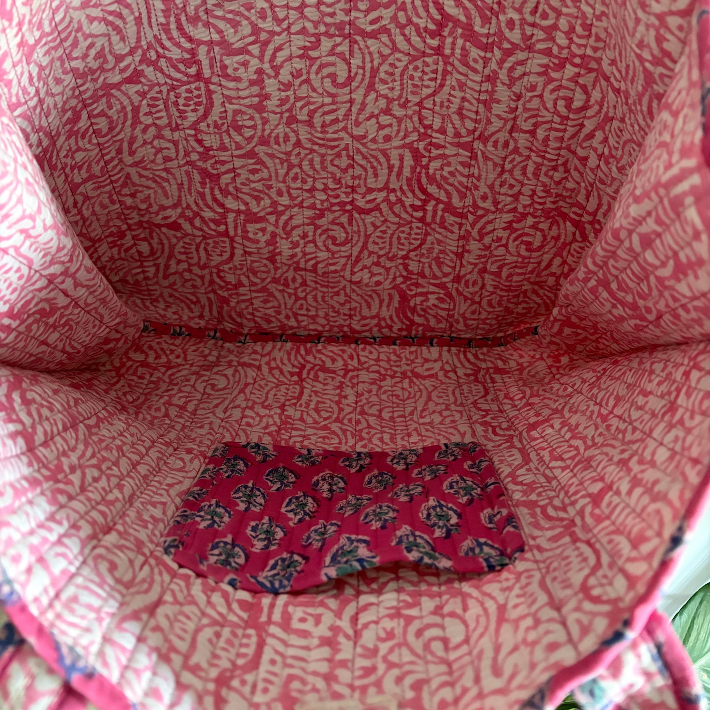 Close-up of a pink patterned fabric bag with a visible brand logo.