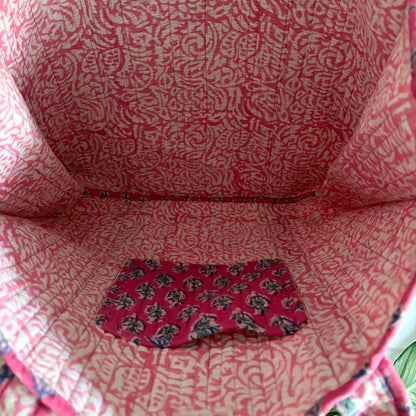 Close-up of a pink patterned fabric bag with a visible brand logo.
