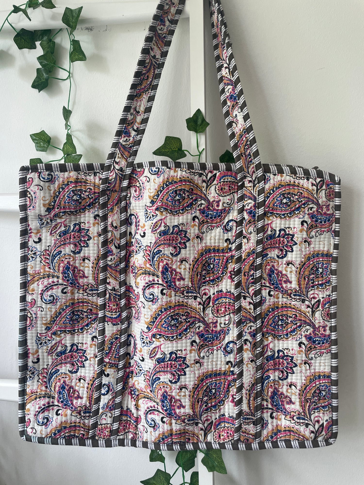 Paisley patterned bag with a strap on a white background