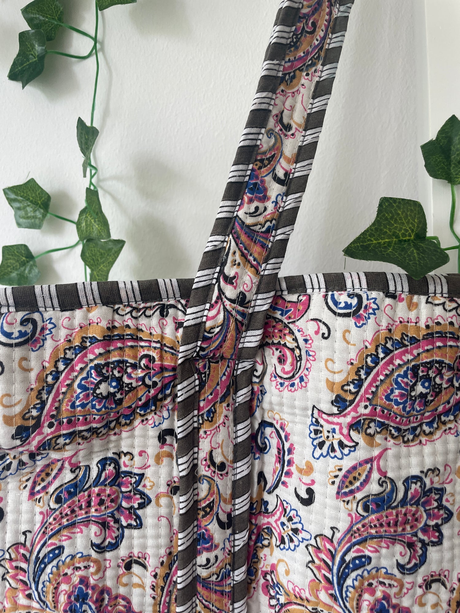 Patterned fabric with paisley design and green leaves in the background