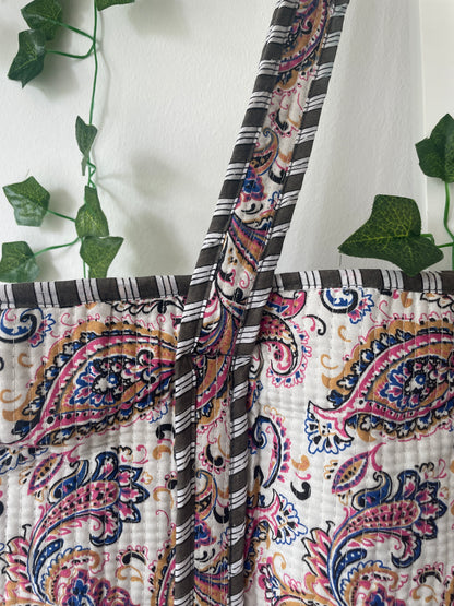 Patterned fabric with paisley design and green leaves in the background