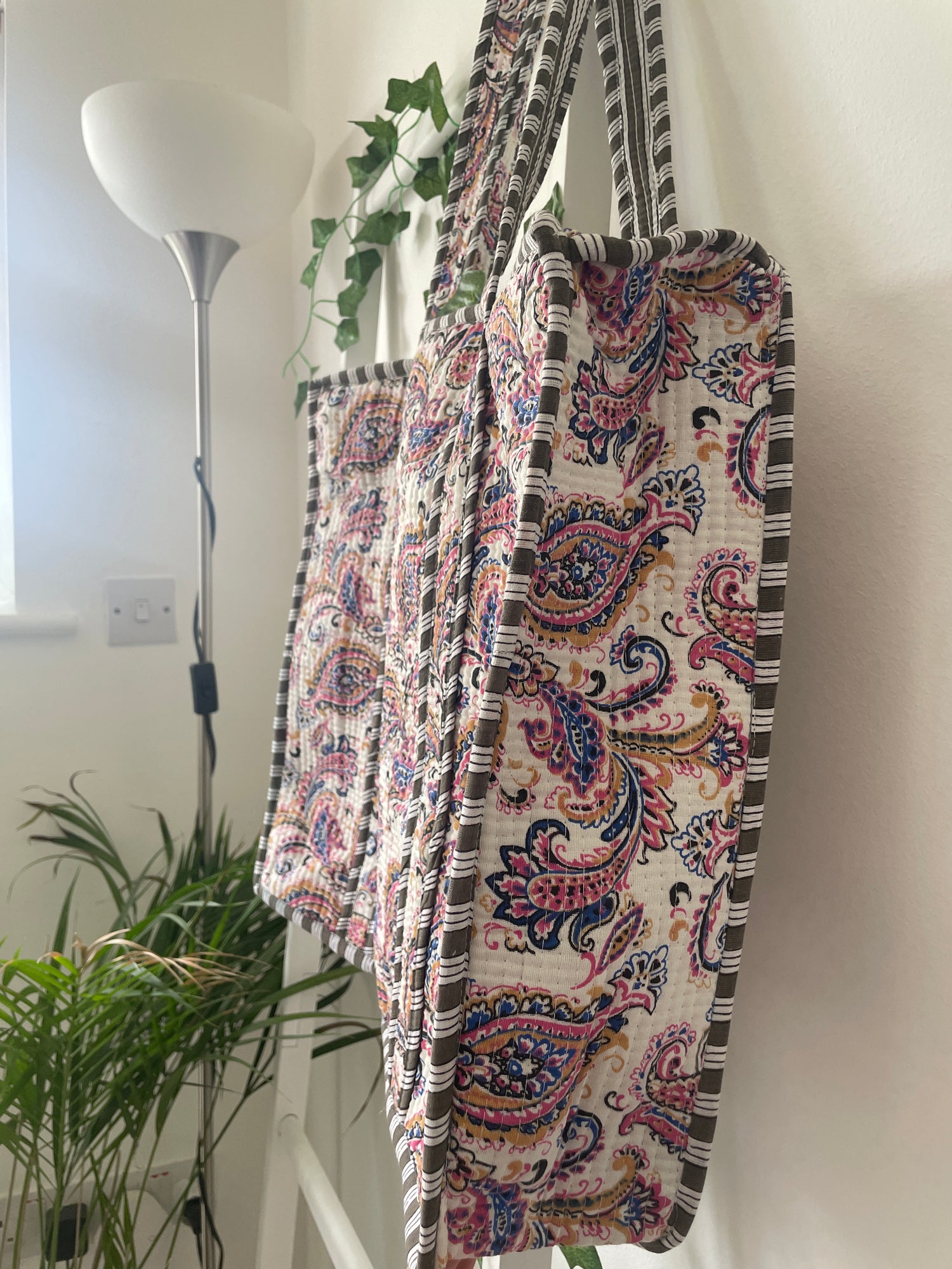 Decorative fabric Tote bag with paisley pattern draped over a white surface.