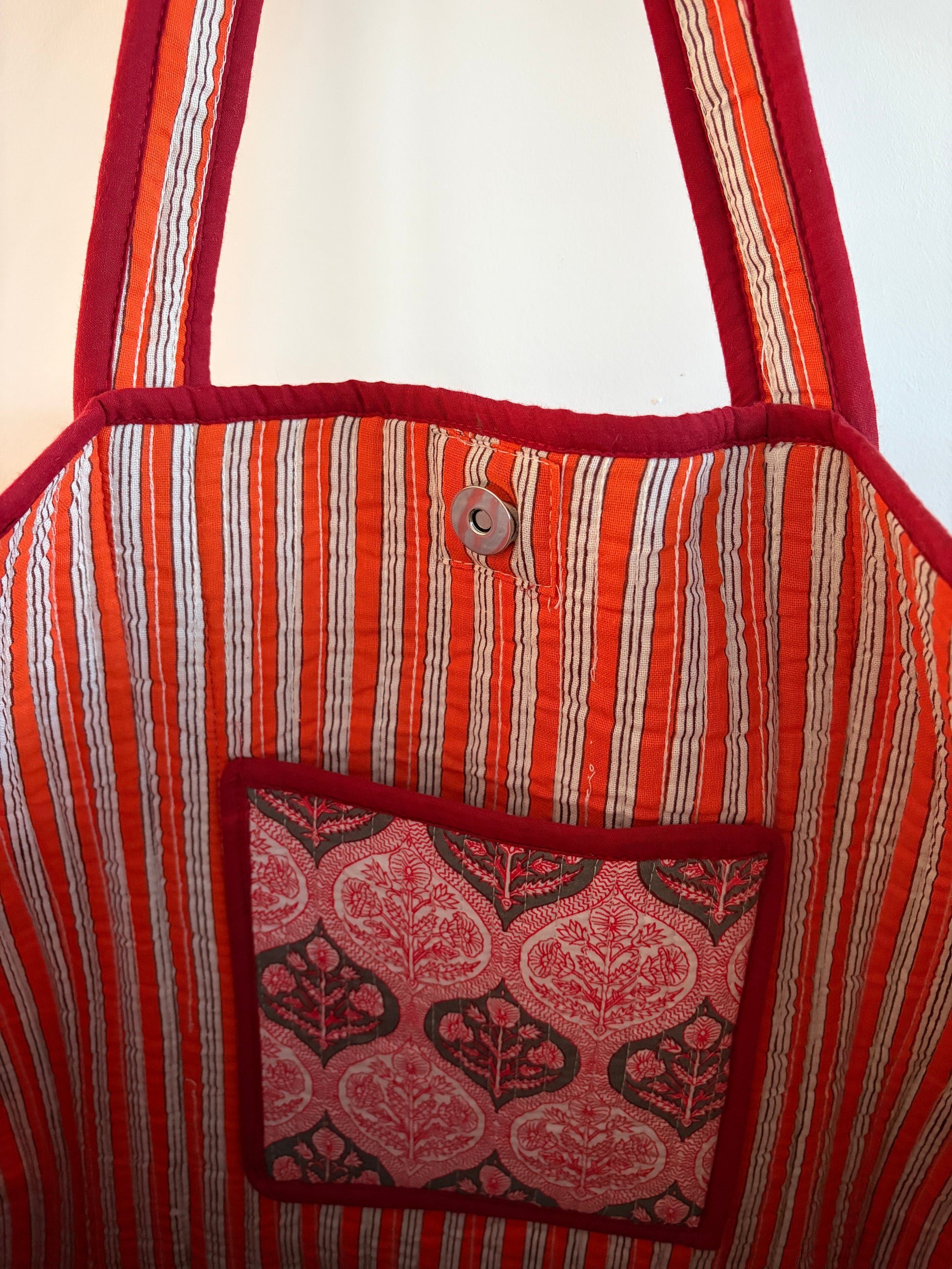 Close-up of a fabric bag with red and orange stripes and a patterned pocket.