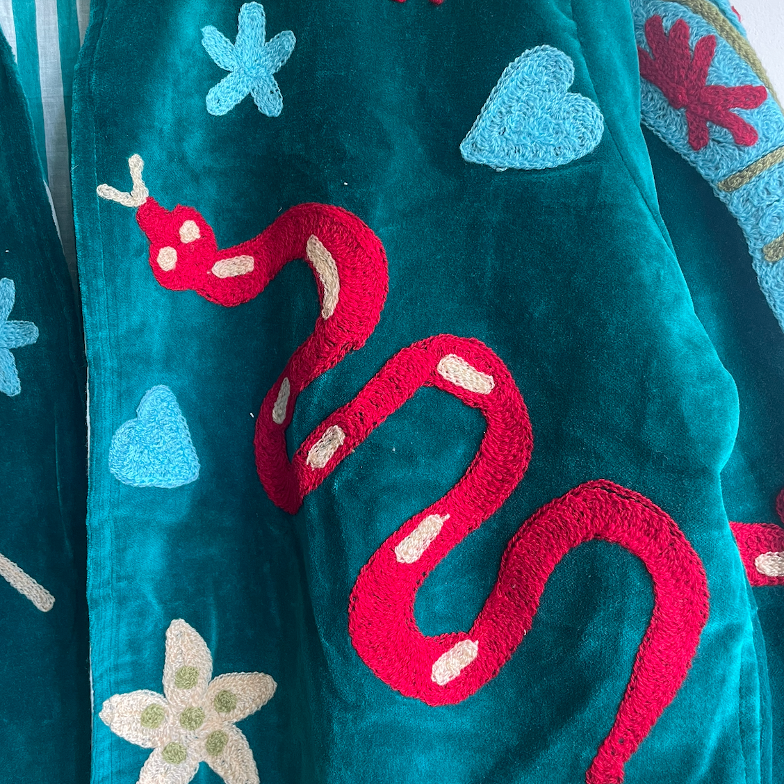 Colorful Suzani jacket on a plain wall.