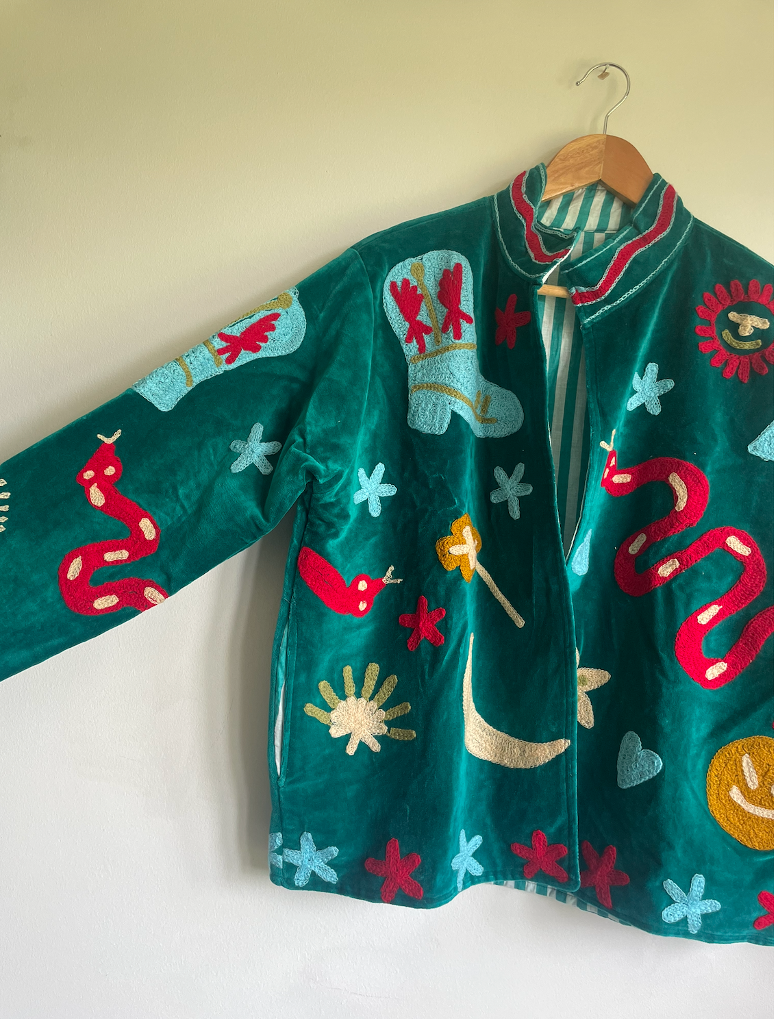 Colorful embroidered jacket on a hanger against a white wall