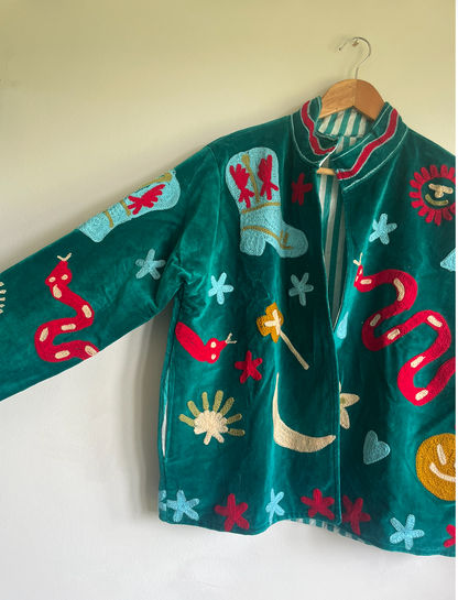 Colorful embroidered jacket on a hanger against a white wall