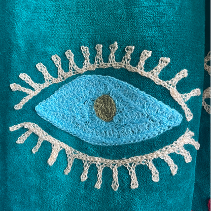 Colorful Suzani jacket on a plain wall.