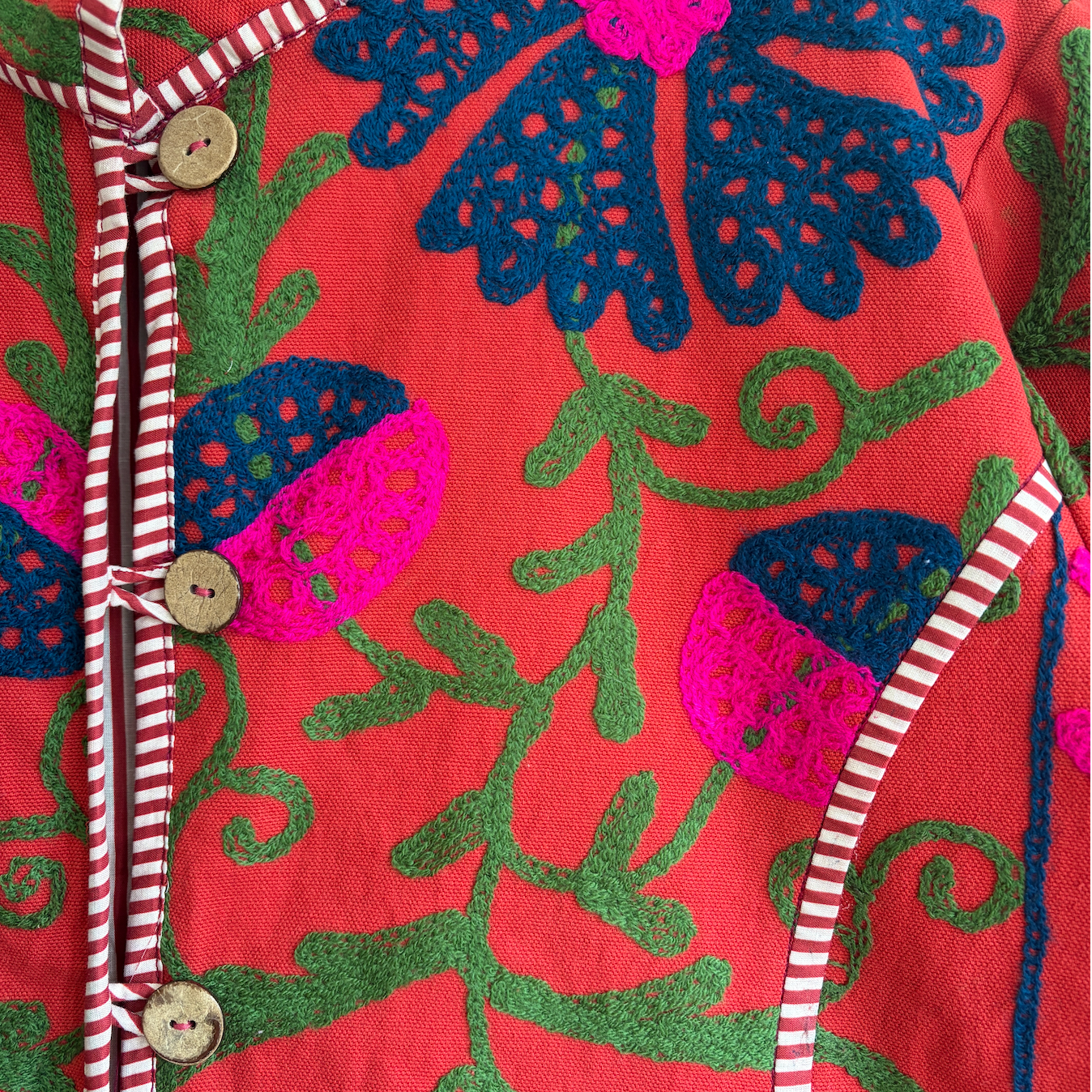 A red Suzani Embroidery jacket with a colorful floral and butterfly pattern. 