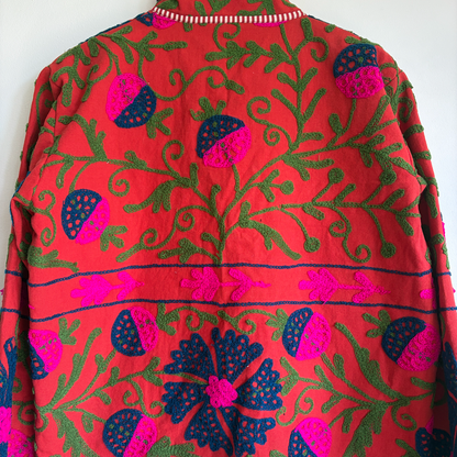 A red Suzani Embroidery jacket with a colorful floral and butterfly pattern. 