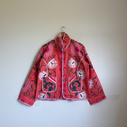 A coral pink embroidered jacket with floral and scroll patterns. 