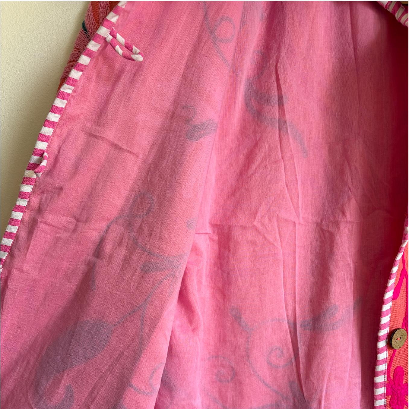 A coral pink embroidered jacket with floral and scroll patterns. 