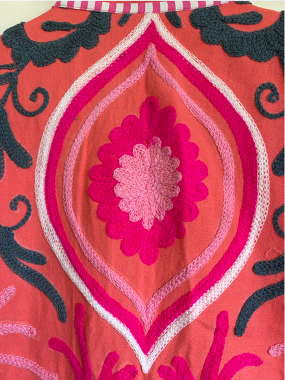 A coral pink embroidered jacket with floral and scroll patterns. 