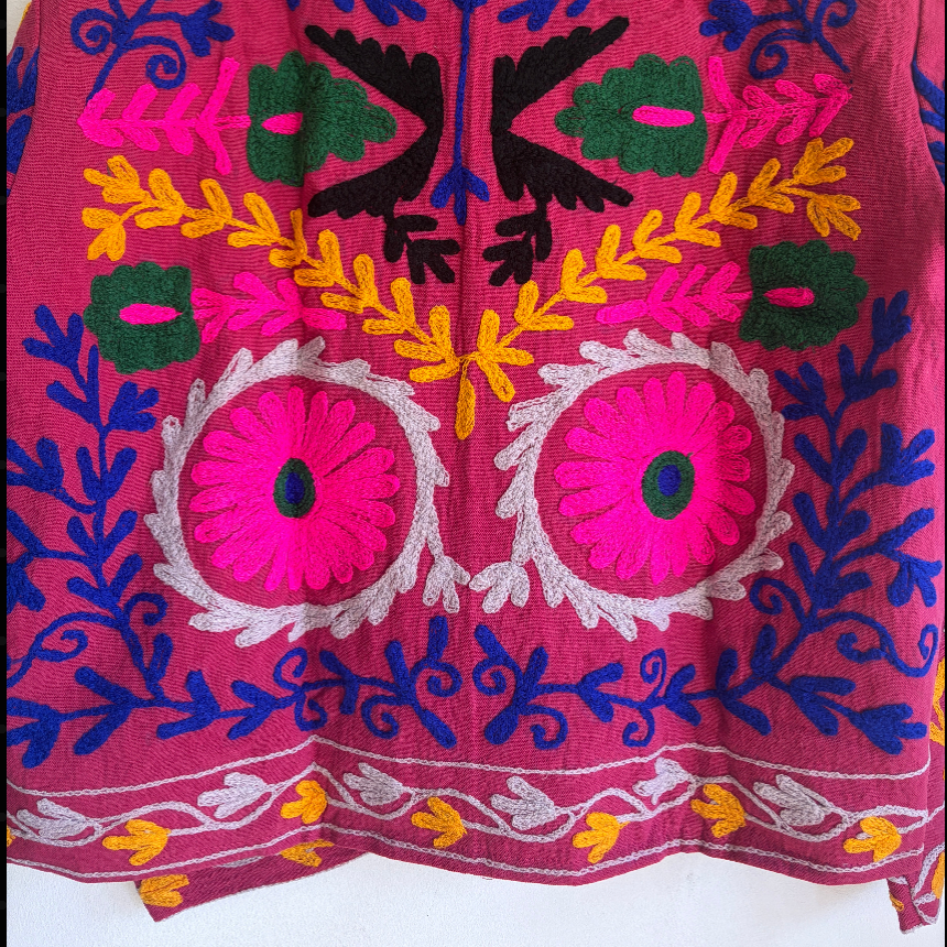 Colorful embroidered jacket on a hanger against a white background
