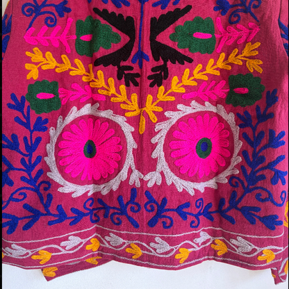 Colorful embroidered jacket on a hanger against a white background