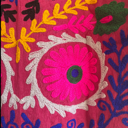 Colorful embroidered jacket on a hanger against a white background