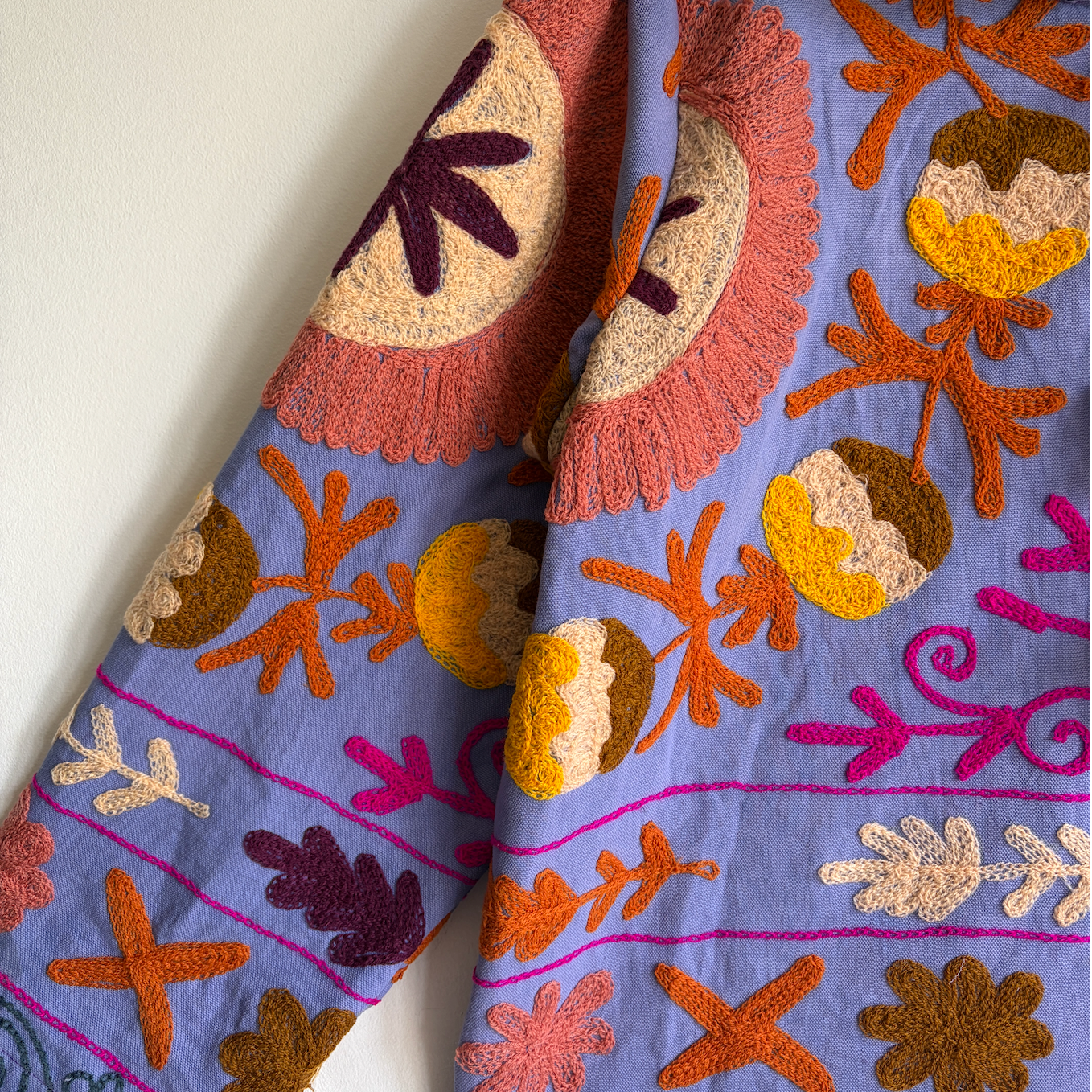 A colorful patterned jacket with a high collar and decorative tassel. 
