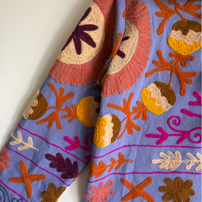 A colorful patterned jacket with a high collar and decorative tassel. 